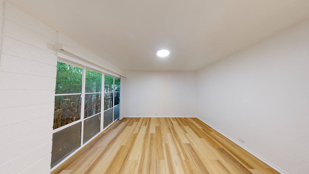 a living room with white walls and wood floors and a large window