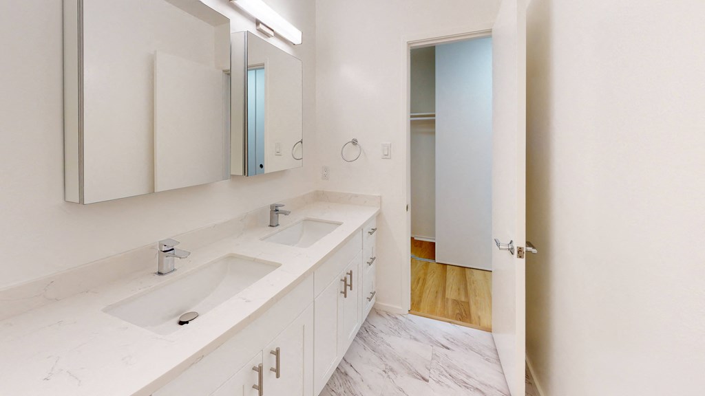 a white bathroom with two sinks and a mirror