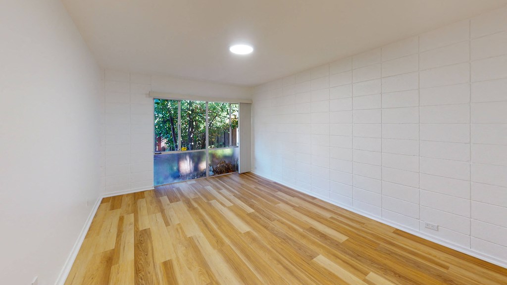 a living room with white walls and wooden floors and a window