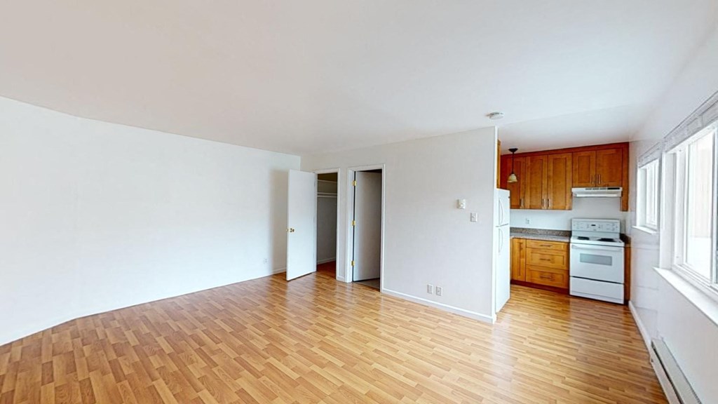 an empty living room and kitchen with wood floors