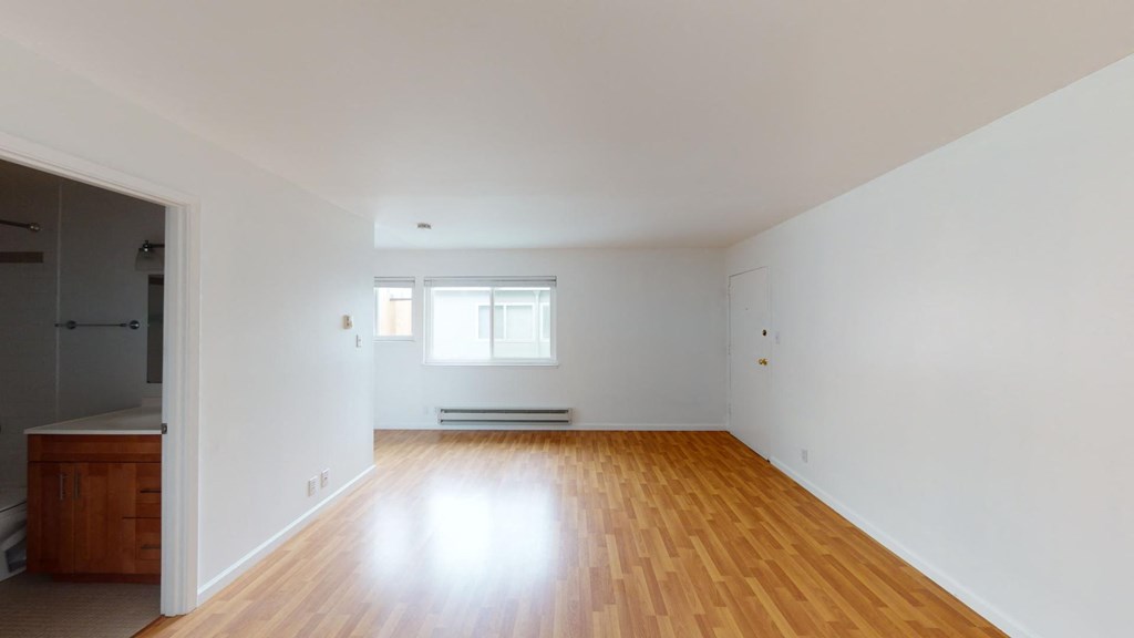 an empty living room with white walls and wooden floors