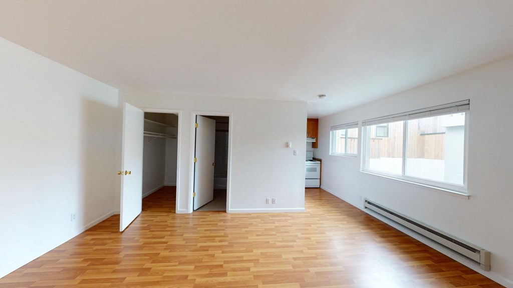 an empty living room with wood floors and white walls