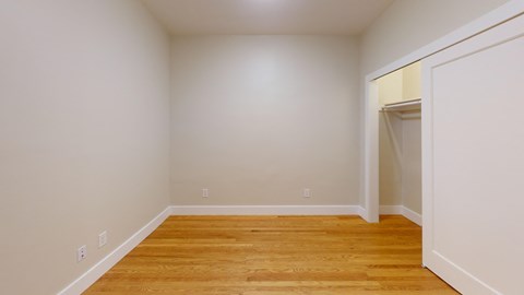 a bedroom with wood flooring and white walls and a closet
