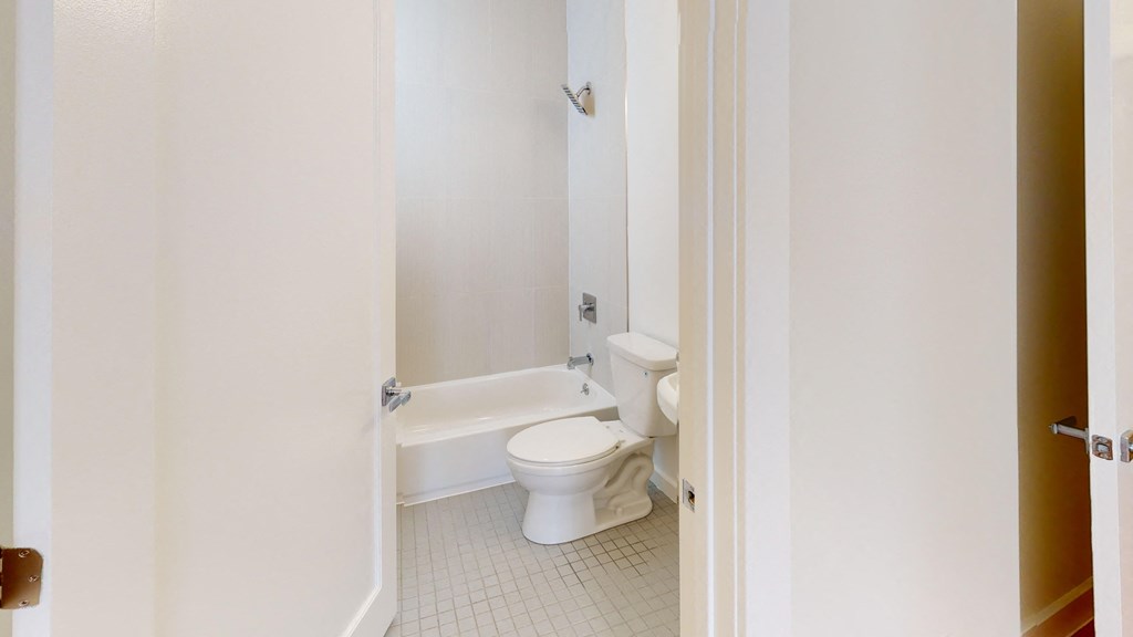 a white bathroom with a toilet and a bath tub