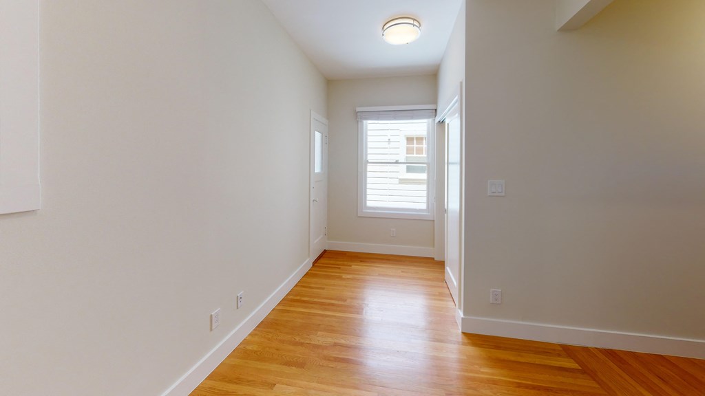 an empty hallway with wood flooring and a window