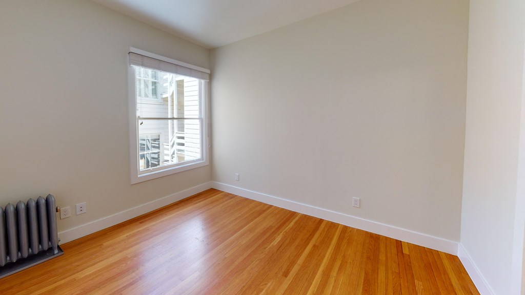 an empty room with wood floors and a window