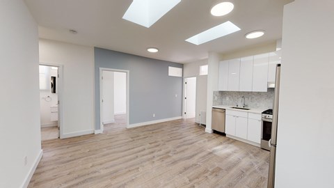 a renovated kitchen and living room with wood floors and white cabinets