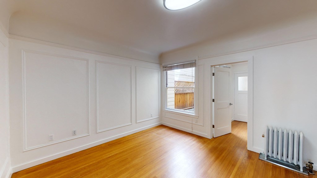 a living room with white walls and a window and a radiator