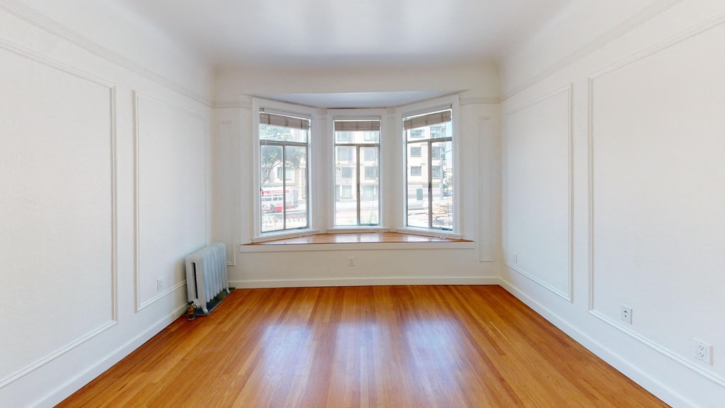 a living room with white walls and a window and wooden floors