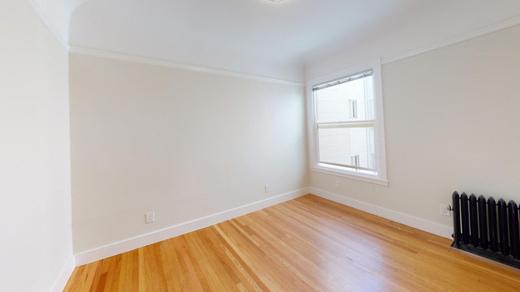a living room with white walls and a window and wooden floors