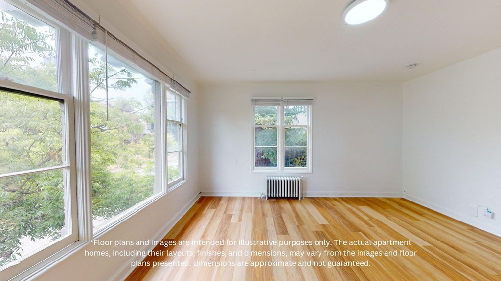 an empty living room with large windows and a wood floor