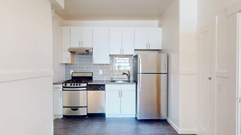 A kitchen with white cabinets and a stainless steel refrigerator.