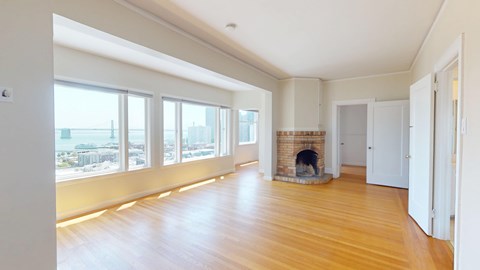 A large, empty room with a fireplace and wooden floors.