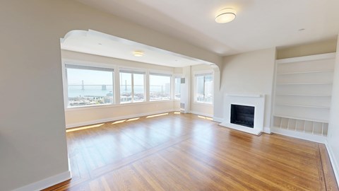 A spacious living room with a fireplace and large windows.