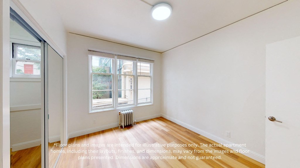 an empty room with a window and a radiator and a mirrored closet
