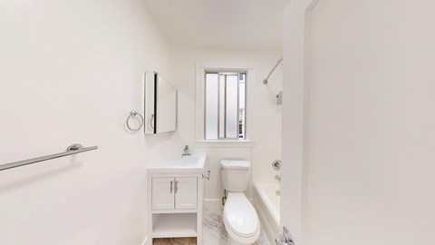 A white bathroom with a toilet, sink, and mirror.