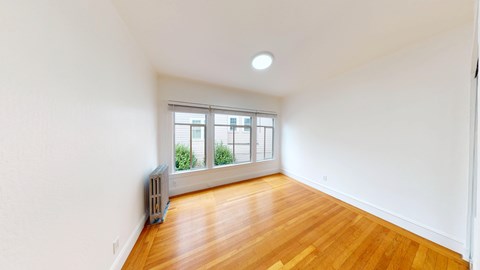 A room with a window and a radiator on the floor.