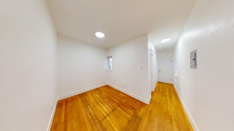 A long hallway with wooden floors and white walls.