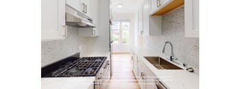 an image of a kitchen with white cabinets and a stove and sink