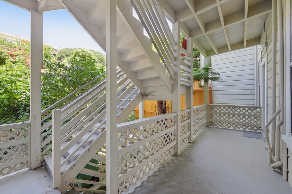 A white staircase with a metal railing leads to a door.