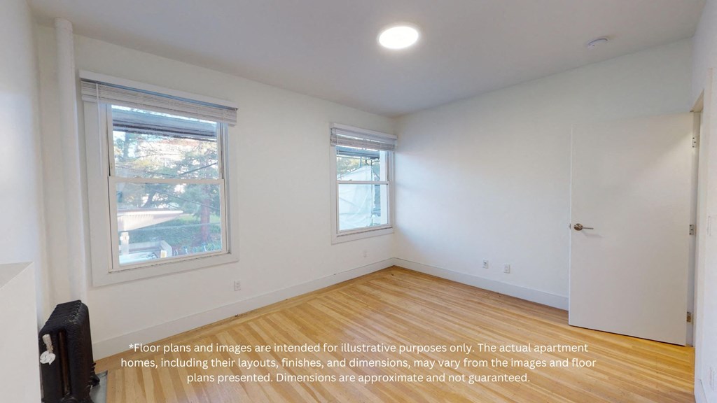 an empty room with a wood floor and two windows