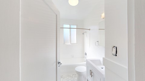 A white bathroom with a toilet, sink, and bathtub.