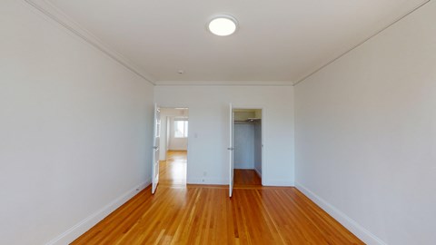 A long hallway with wood floors and white walls.