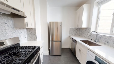 A kitchen with a stove, refrigerator, and washing machine.