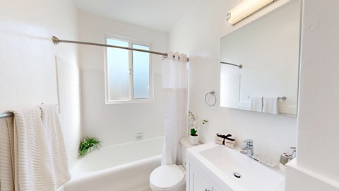 A white bathroom with a tub, toilet, sink, and mirror.