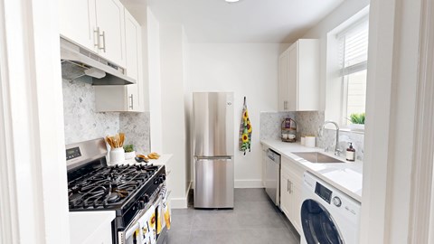 A modern kitchen with a stove, refrigerator, and washing machine.