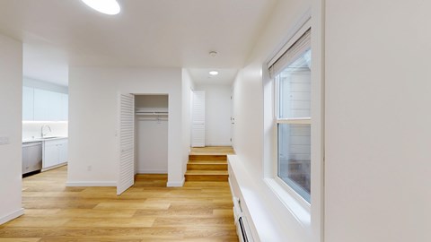 A spacious, well-lit room with wooden floors and white walls.