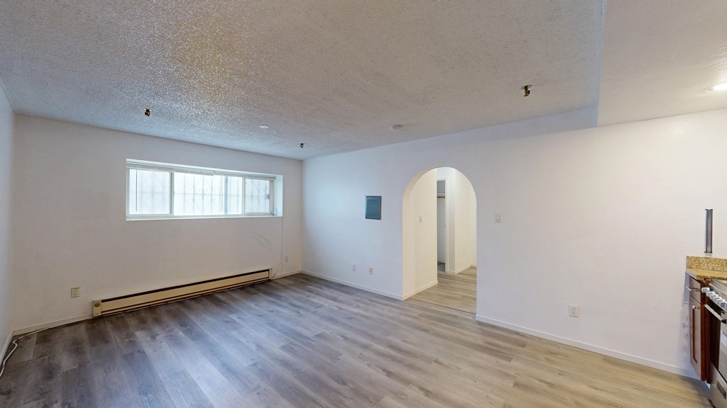 A room with a window and a doorway leading to another room.