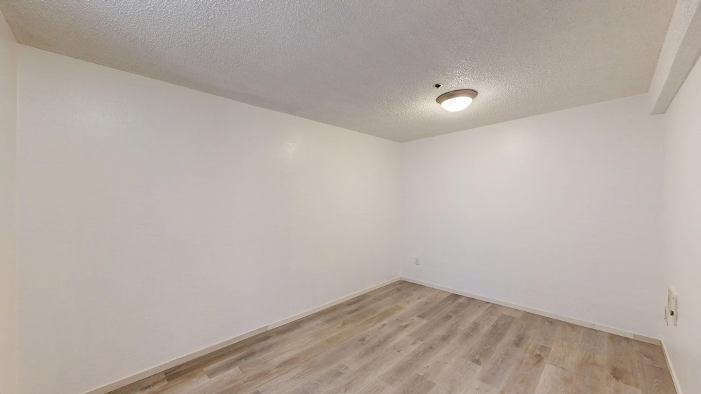 A room with wooden flooring and white walls.