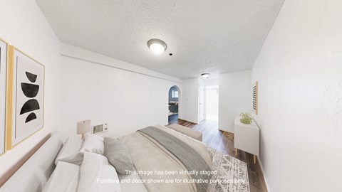 A bedroom with a bed, a nightstand, and a window.