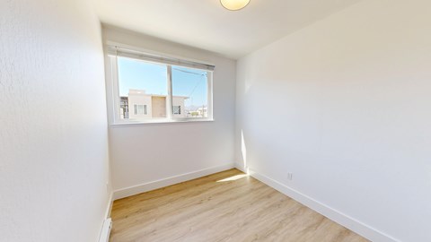 A room with a window overlooking a street with buildings.