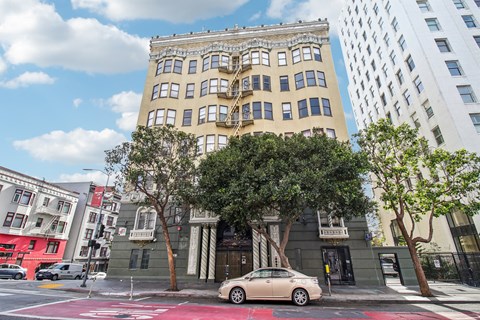 A white car is parked on the street in front of a building.