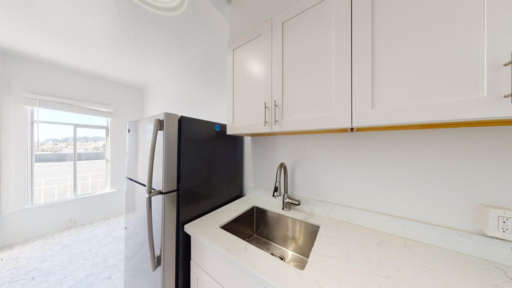 a kitchen with white cabinets and a sink and a refrigerator