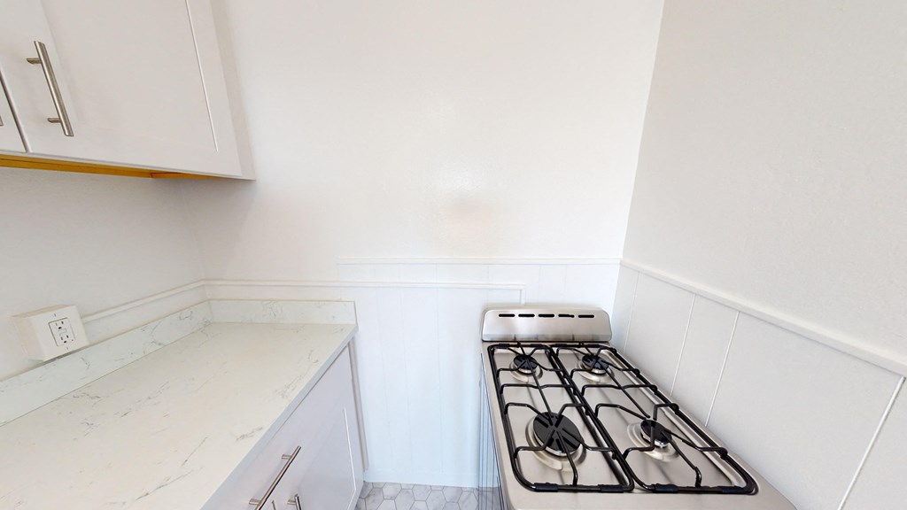 a small kitchen with white cabinets and a stove