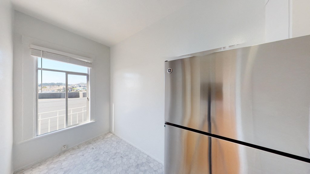 an empty room with a refrigerator and a window