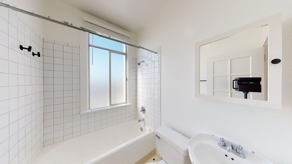 a white bathroom with a tub and a sink and a window