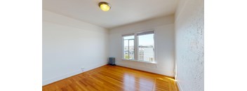 an empty living room with wood floors and a window
