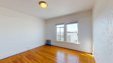 an empty living room with wood floors and a window