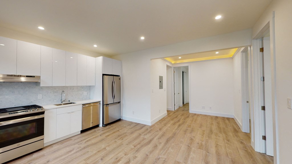 a kitchen and living room with white cabinets and a wood floor
