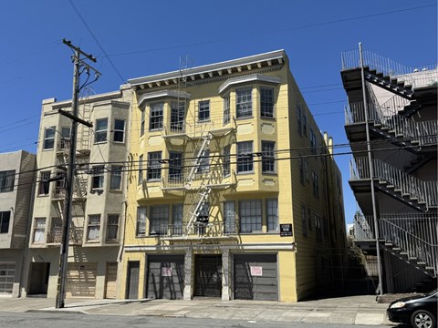 A yellow building with a black car parked in front.
