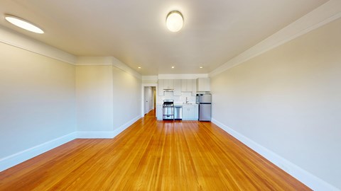 A long empty room with wooden floors and white walls.