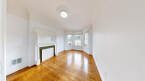 A room with a fireplace and wood flooring.