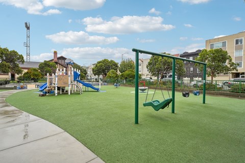 A playground with a green swing set and a blue slide.