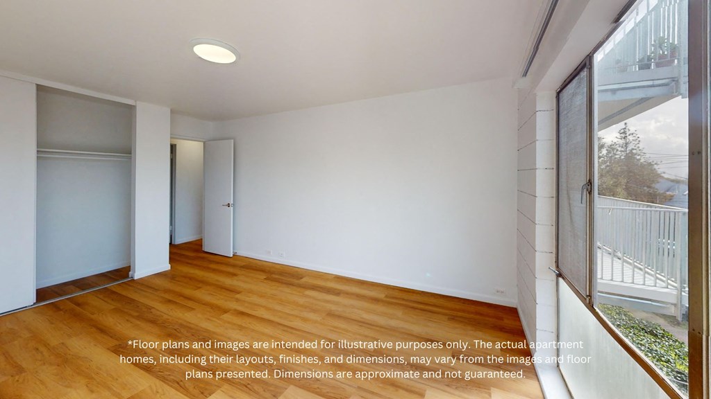 an empty living room with wood flooring and large windows