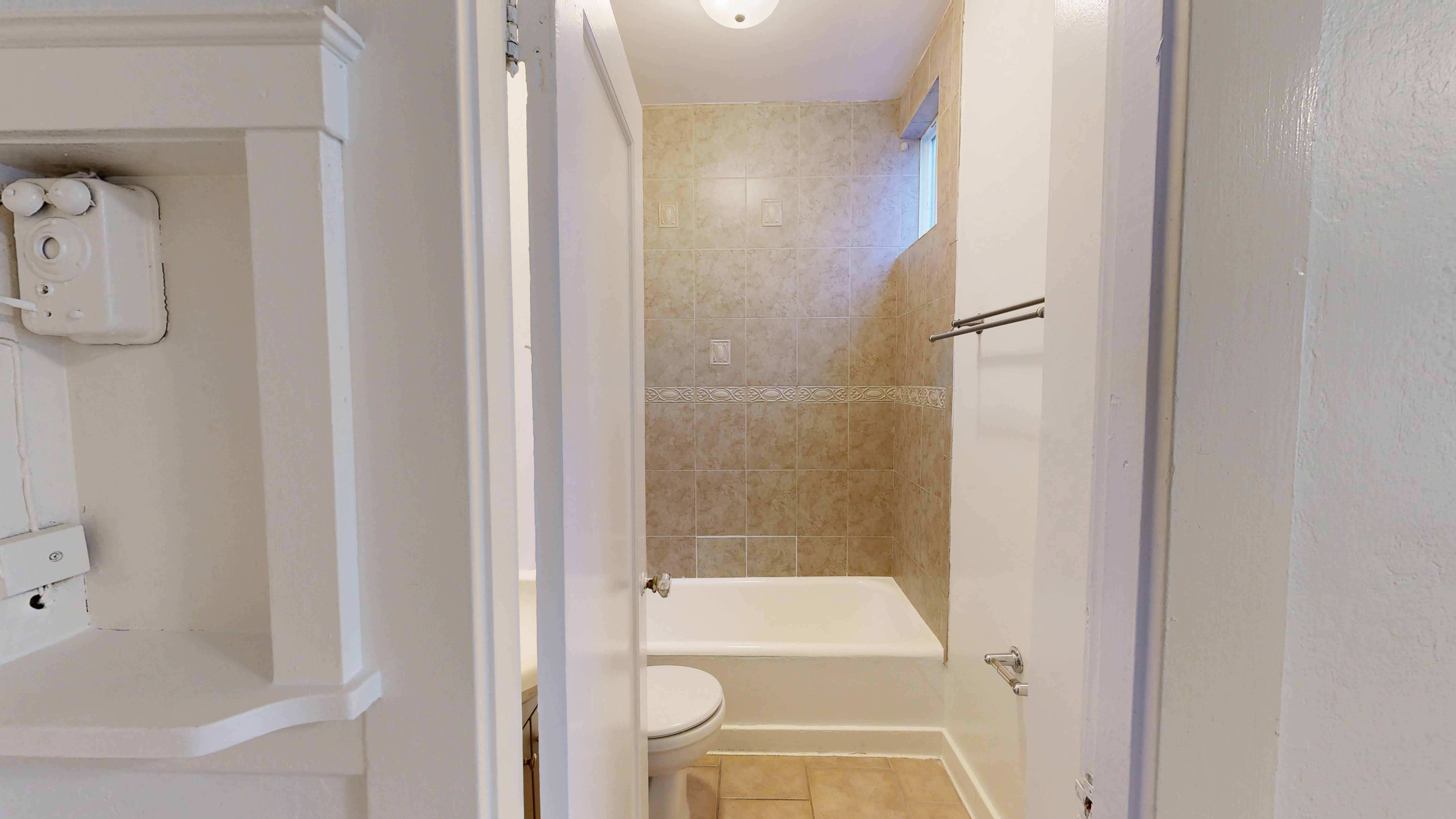 A white bathroom with a toilet, sink, and shower.