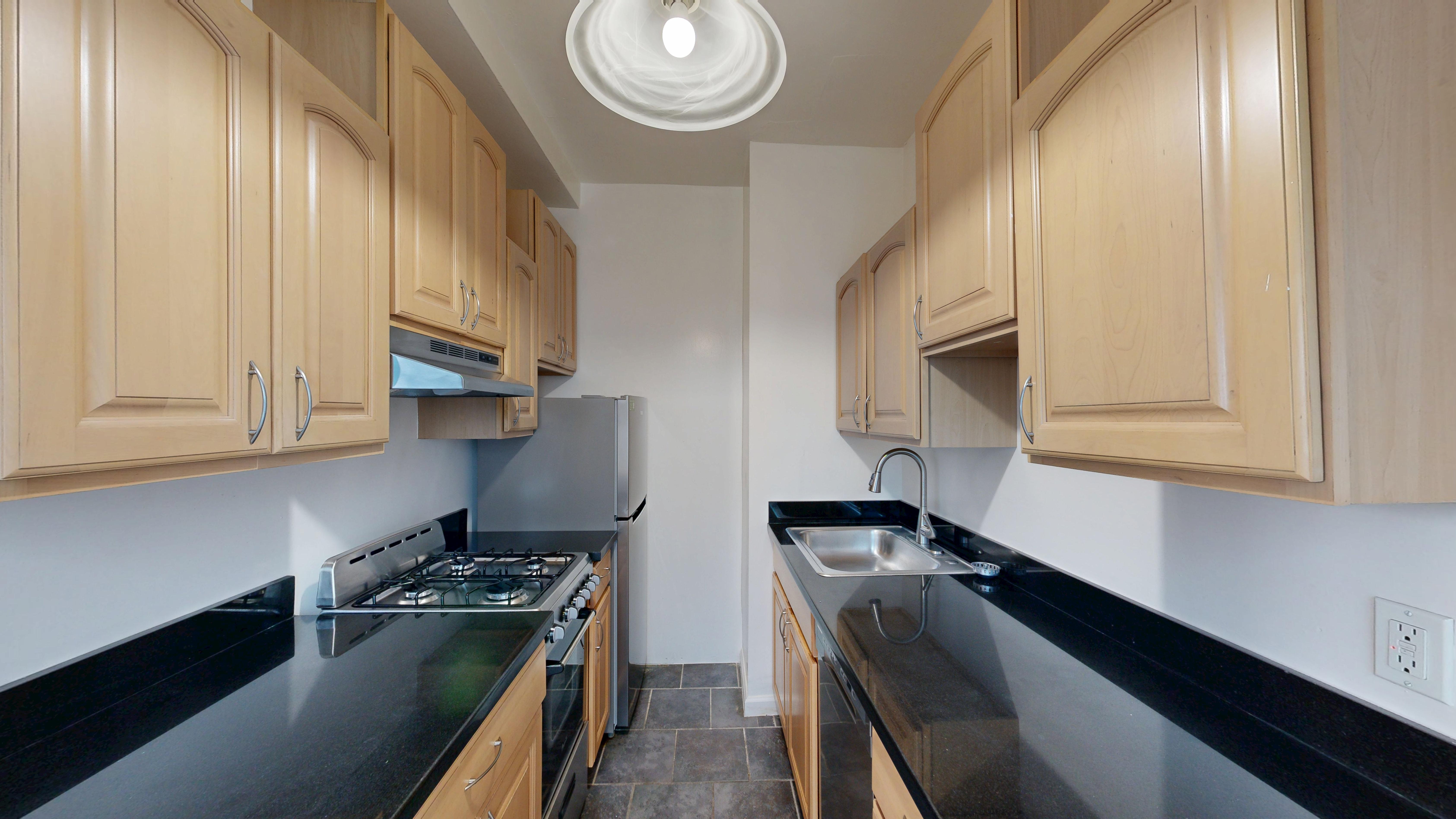 A kitchen with wooden cabinets and black countertops.